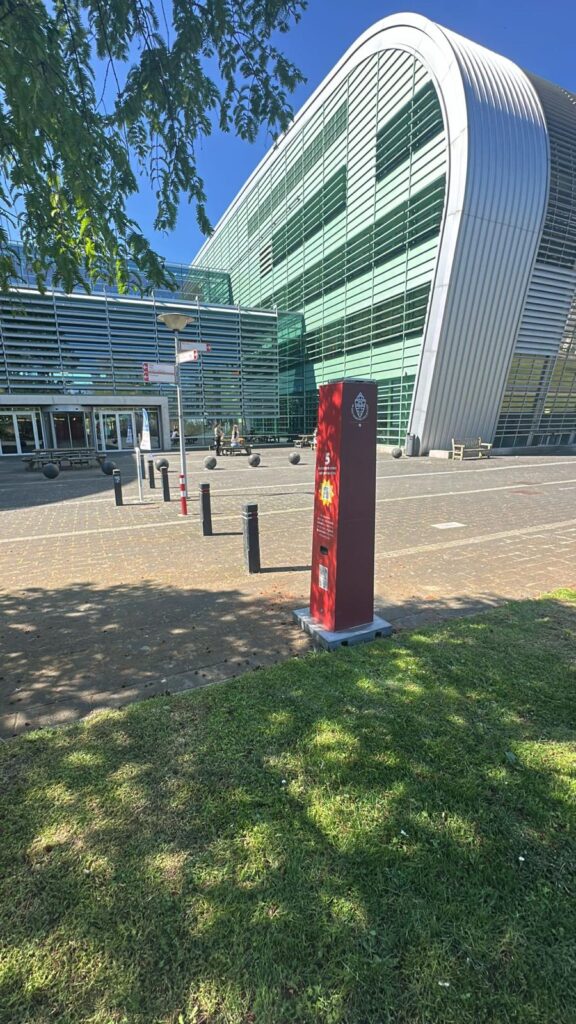 Rote Sonnencreme-Station im Design der Radboud-Universität mit kostenloser Sonnencreme auf dem Campus in Nimwegen